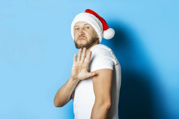 Man in a Santa Claus hat makes a repulsive gesture with his hand — Stock Photo, Image