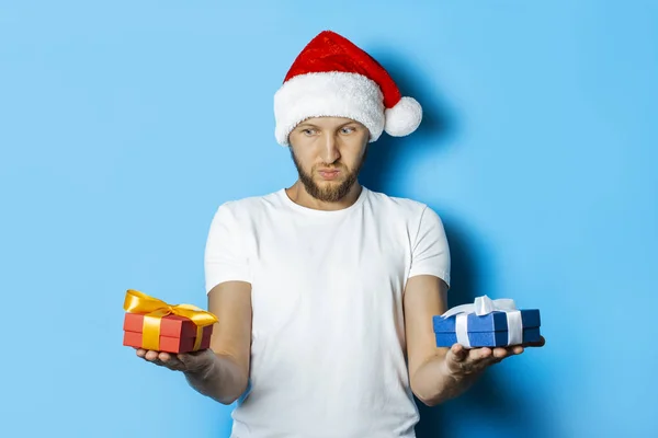 Mann mit nachdenklichem Gesicht im Weihnachtsmann-Hut hält Geschenke in der Hand — Stockfoto