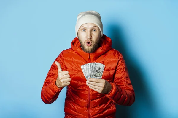 Man with a surprised face in a hat and a red jacket parka holds