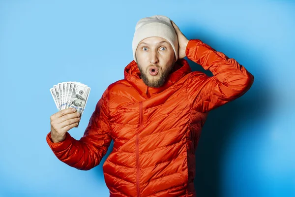 Man with a surprised face in a hat and a red jacket parka holds