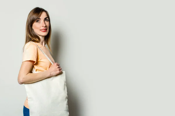 ショッピングバッグを肩に背景にライトをつけた若い女性 — ストック写真