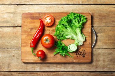 Ahşap bir arka planda kesme tahtasındaki sebzeler. Uzayı kopyala, düzleştir, yatır.