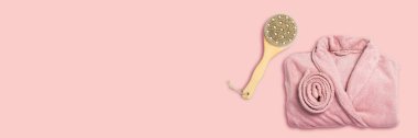 Pembe bornoz ve masaj fırçası, pembe arka planda. Uzayı kopyala, düz yat. Pankart.