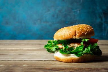 Taze ev yapımı iştah açıcı hamburgerle ahşap masada tavuk..