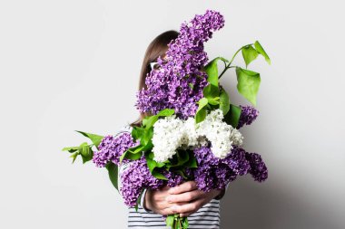 Bir buket ışık arkaplanı tutan genç bir kadın yüzü görünmüyor.