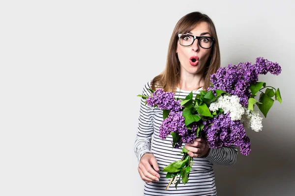 Mujer Joven Sorprendida Gafas Sostiene Ramo Lilas Sobre Fondo Claro — Foto de Stock