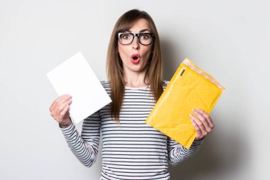 Şaşırmış bir yüzü olan genç bir kadın, arka plandaki bir zarftan bir mektup ya da uyarı alır. Üniversiteden konsept mektup, vergiler, bilet.