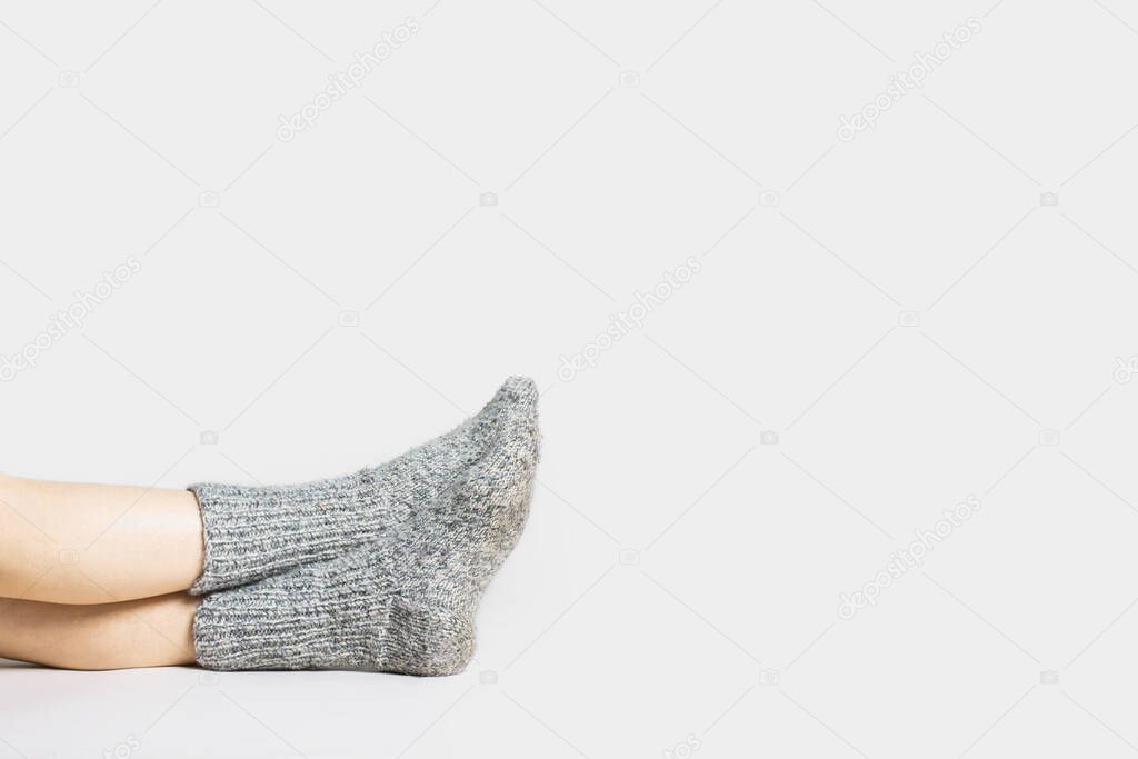 Woman sits on the floor in warm gray socks on a light background. Only legs visible.