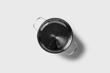 Işık arka planında kapağı olmayan boş metal bir tava. Üst manzara, düz uzanma.