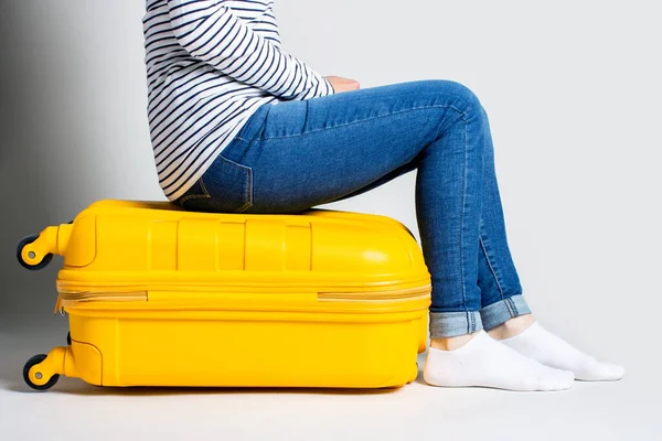 Mujer Está Sentada Sobre Una Maleta Plástico Amarillo Sobre Fondo —  Fotos de Stock