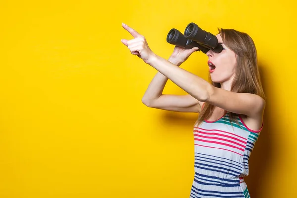 Çizgili Elbiseli Genç Bir Kadın Dürbünle Bakar Sarı Arka Planı — Stok fotoğraf