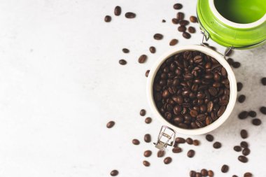 Taze kahve çekirdekleri ve kahve çekirdekleri ile dolu kavanoz beton zemine saçılmıştır. Pankart. Taze kahve, kahvaltı, çiftlik. Üst manzara, düz uzanma.