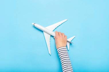 Kadın eli mavi arka planda bir uçağı tutuyor. Konsept uçuş, biletler, rezervasyon, uçuş araması, seyahat. Pankart. Düz yatış, üst görünüm.