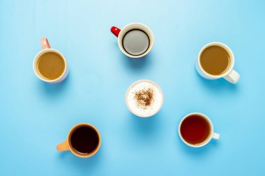 Cups with hot drinks, coffee, cappuccino, coffee with milk on a blue background. Concept coffee shop, meeting friends, breakfast with friends, friendly team. Banner. Flat lay, top view. clipart
