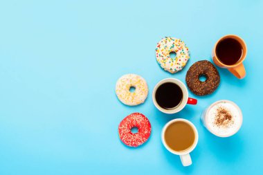 Lezzetli çörekler ve mavi arka planda sıcak içecekler. Tatlılar, fırınlar, pastalar, kahveciler, arkadaşlar, dost canlısı takım kavramı. Düz yatış, üst görünüm.