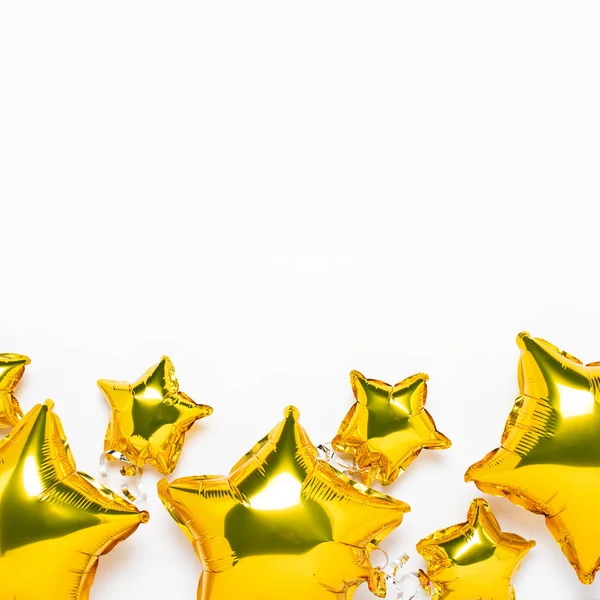 Hava altın balonları yıldız şeklinde ve beyaz arka planda şekerler. Tatil, parti, fotoğraf bölgesi, dekorasyon. Banner Düz yatar, üst görünüm.