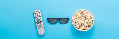 Patlamış mısırlı kase, Imax gözlükleri, mavi arka planda televizyon için uzaktan kumanda. Ev sineması kavramı, sinemanın yenilikleri, boş zaman. Düz yatış, üst görünüm.