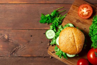 Hamburger yapmak için gerekli malzemeler. Koyu ahşap bir arka planda hamburger. Üst manzara, düz uzanma.