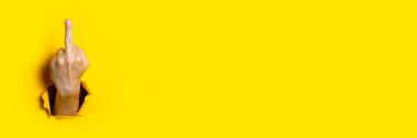 Man's hand showing middle finger, fuck on a yellow background. Hand gestures. Banner