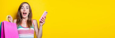 Şok olmuş genç bir kız elinde telefon çantasıyla sarı arka planda bekliyor. Pankart