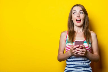 Sarı arka planda telefonu olan mutlu, genç bir kadın..