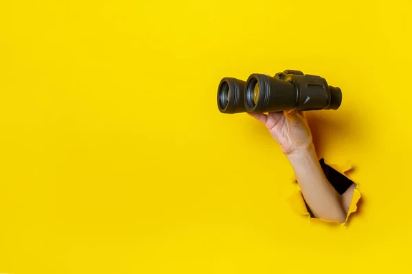 Mano Femenina Sostiene Binoculares Negros Sobre Fondo Amarillo Mirando Través — Foto de Stock