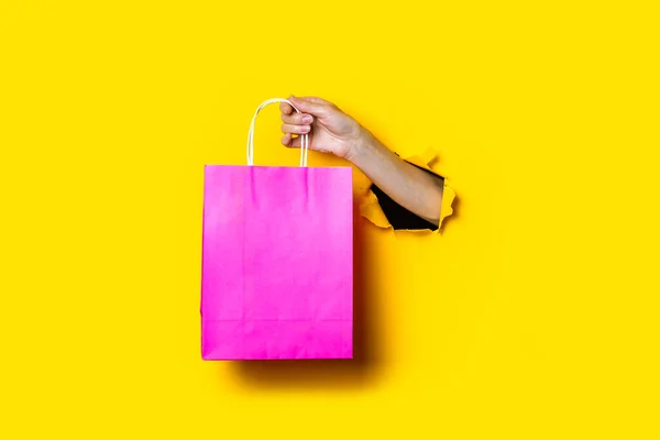 Mão Feminina Segura Pacote Rosa Com Compras Fundo Amarelo — Fotografia de Stock