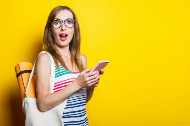 Sarı arka planda telefon tutan bir çantanın içindeki genç kadın Karimat 'a şaşırdım.