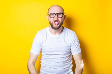 Gözlüklü kızgın genç adam sarı arka planda dişlerini gösteriyor.