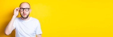 Sarı arka planda gözlüklü ciddi sakallı genç adam. Pankart