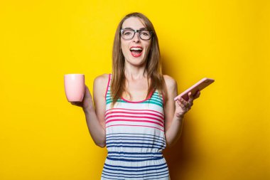 Dost canlısı genç bayan telefondan ve sarı arka planda kahve fincanından memnun..