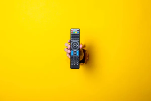 Χέρι Του Ανθρώπου Κρατά Ένα Τηλεχειριστήριο Τηλεόρασης Φωτεινό Κίτρινο Φόντο — Φωτογραφία Αρχείου