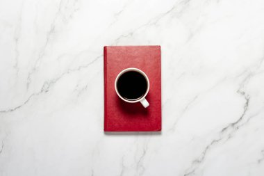 Kahve, çay ve kırmızı bir kitapla mermer bir masada. Kahvaltı, eğitim, bilgi, kitap okuma kavramı. Düz yatış, üst görünüm.