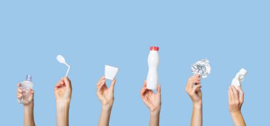 Açık mavi arka planda çöpleri tutan eller. Ayrı çöp kavramı, plastiği durdur, geri dönüşümü durdur.