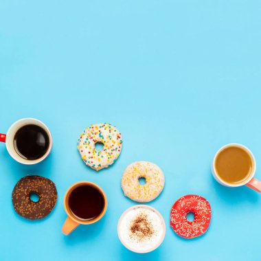 Lezzetli çörekler ve bardaklar sıcak içecekler, kahve, kapuçino, mavi arka planda çay. Şeker, fırın, hamur işi, kahve dükkanı, toplantı, arkadaşlar, arkadaş takımı kavramı. Kare. Düz yatış, üst görünüm.