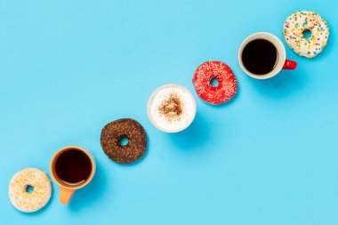 Lezzetli çörekler ve bardaklar sıcak içecekler, kahve, kapuçino, mavi arka planda çay. Şeker, fırın, hamur işi, kahve dükkanı, toplantı, arkadaşlar, arkadaş takımı kavramı. Düz yatış, üst görünüm.