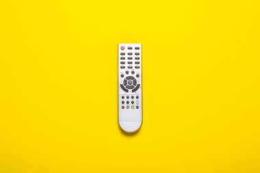 Sarı arka plandaki televizyon ya da televizyon ayarlayıcılarından uzaktan kumanda. Kavram serisi, film, spor. Pankart. Düz yatış, üst görünüm.