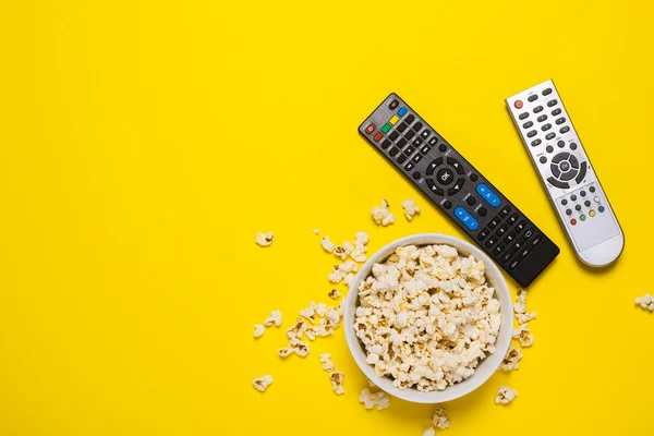 Dois Controles Remotos Sintonizador Uma Tigela Pipoca Fundo Amarelo Série — Fotografia de Stock