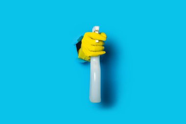 Sarı eldivenler içinde parlak mavi arka planda sprey tutuyorlar..