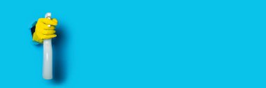Sarı eldivenli, parlak mavi arka planda sprey tutan eller. Pankart
