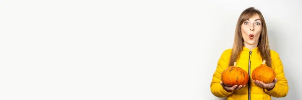 Шокована Молода Дівчина Жовтій Куртці Тримає Дві Гарбузи Світлому Фоні — стокове фото