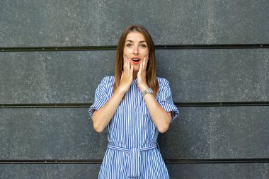 Taş bir duvarın arkasında elbisesi olan, şaşırmış yüzlü genç bir kadın..