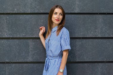 Genç, dost canlısı bir kadın, taş duvarın arka planına bakıyor..