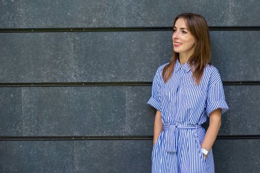 Taş bir duvarın arkasında giyinmiş, dost canlısı genç bir kadın..