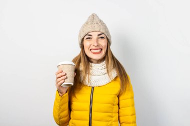 Sarı ceketli ve şapkalı genç bir kadın elinde hafif arka planda kahve olan bir kağıt bardak tutuyor. Kavramsal kahve dükkanı, kahveci, sıcak içecek. Pankart.