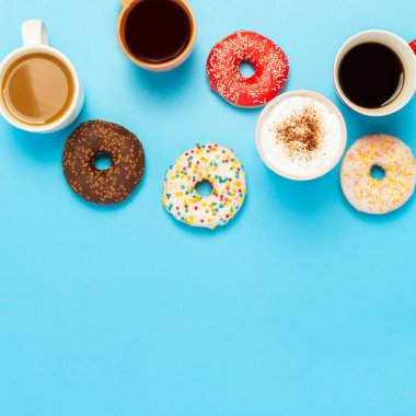 Lezzetli çörekler ve bardaklar sıcak içecekler, kahve, kapuçino, mavi arka planda çay. Şeker, fırın, hamur işi, kahve dükkanı, toplantı, arkadaşlar, arkadaş takımı kavramı. Kare. Düz yatış, üst görünüm.