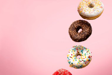 Pembe arka planda havada donutlar uçuşuyor. Fırın, fırın konsepti. Havalanma. Pankart.