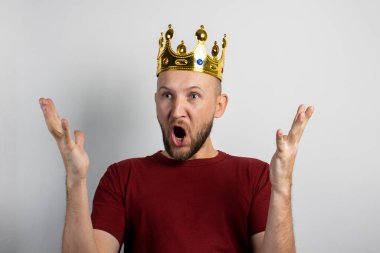 Kafasında taç olan genç adam seviniyor ya da arka planda bir şeyleri kutluyor. Kavram, kral, şans, kazanç, zenginlik, hayal, amaç, istektir. Pankart.