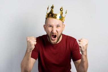 Kafasında taç olan genç adam seviniyor ya da arka planda bir şeyleri kutluyor. Kavram, kral, şans, kazanç, zenginlik, hayal, amaç, istektir. Pankart.