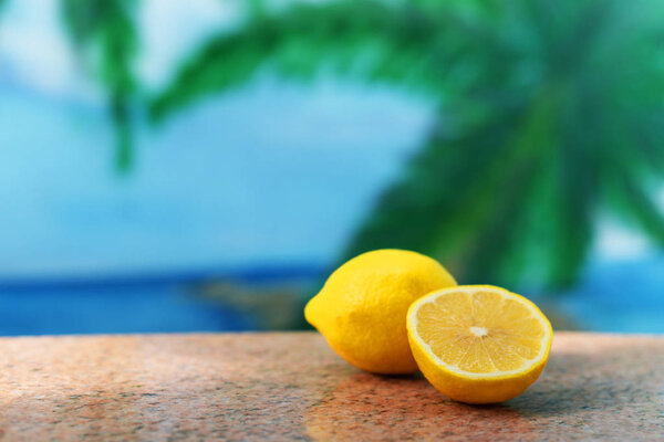 ripe fruit sour lemon yellow on a table on a background of sunny and palm trees